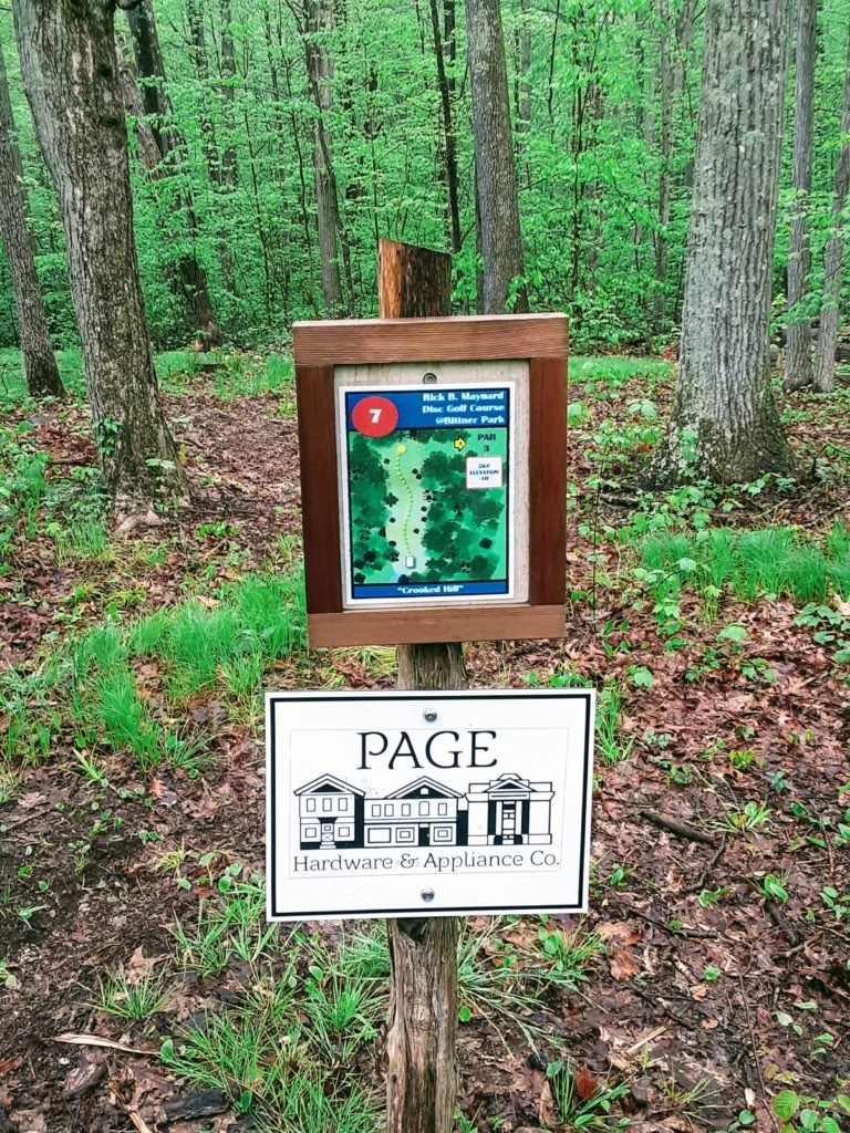 sign of disc golf hole with advertisement below