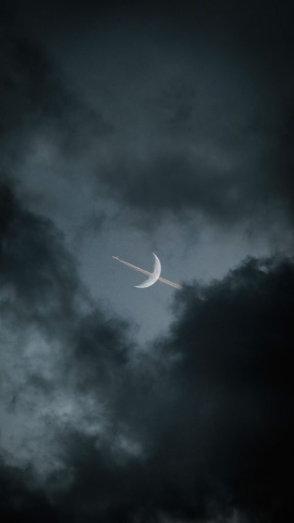 white airplane in mid air under gray clouds
