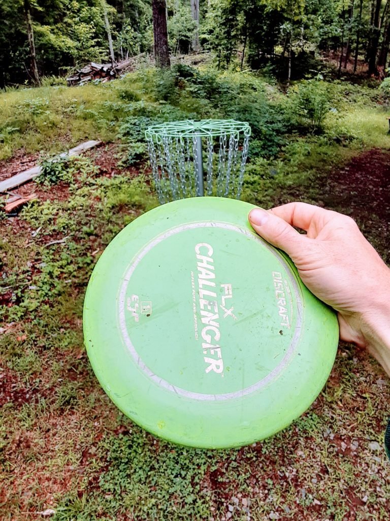 green disc in front of green disc golf basket