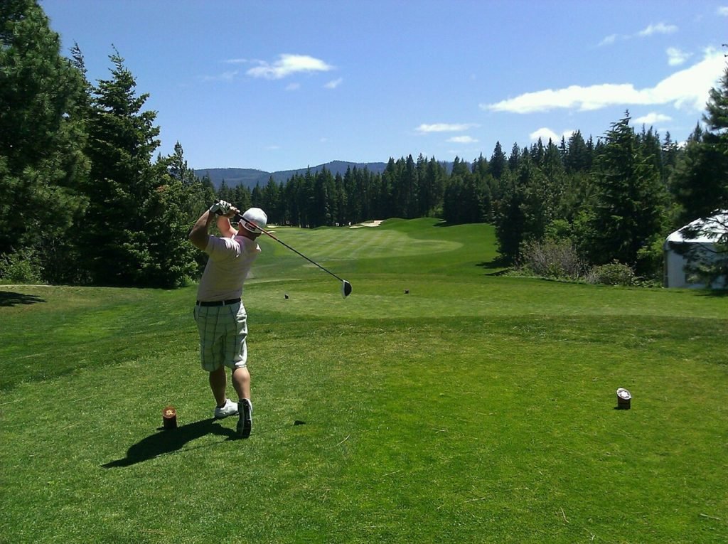 person in backswing after golf tee shot