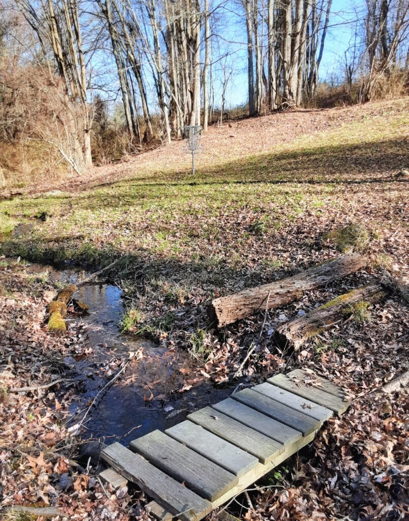 View of wooden bridge over a brook at Northampton State Hospital Disc Golf Course.