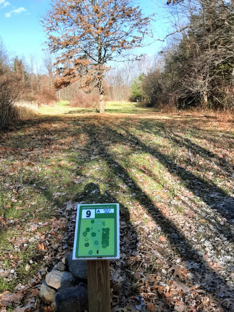View of open field for hole 9 at Northampton State Hospital Disc Golf Course.