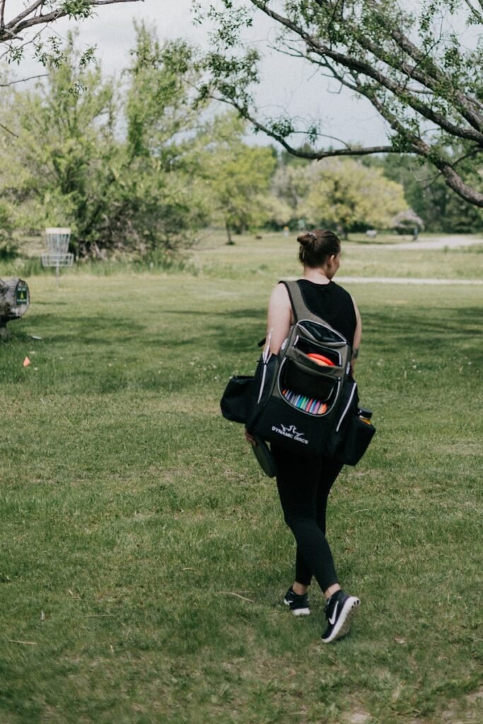 a person walking on a grass field without a disc golf sling bag