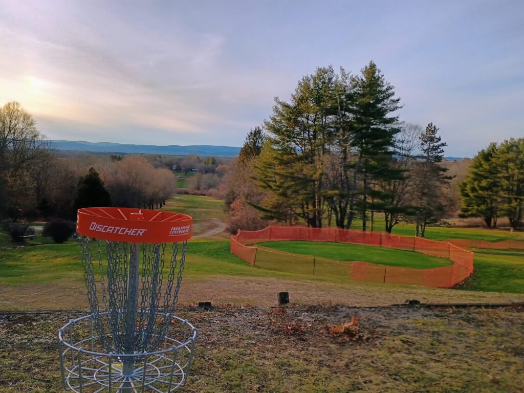 view of red disc golf basket on top a hill with big view at top of cherry hill disc golf course